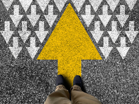 Different thinking and Business and technology disruption concept. Yellow big arrow opposite direction with white arrow on road asphalt.