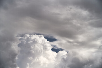 A piece of a blue sky with many clouds around. Midday cloudscape in the summer sky.