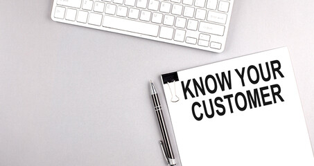 KNOW YOUR CUSTOMER text on paper with keyboard on grey background
