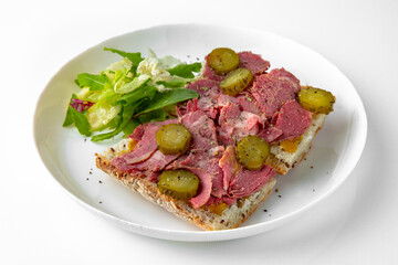 Sandwich with beef pastrami with pickles. Balanced, nutritious, tasty and nutritious food. Ready-made menu for a restaurant or for delivery. Dish in a white plate isolated on a white background.