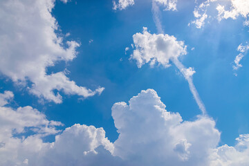 Engine exhaust contrails in the blue cloudy sky.