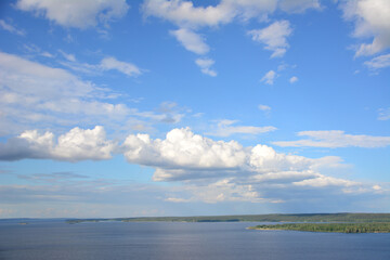 Obraz premium chain of white clouds in blue sky flying over river, close-up