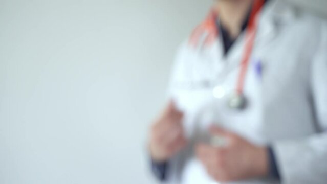 Out of focus doctor putting on stethoscope over shoulders and crossing arms