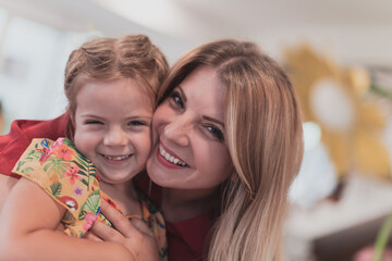 A cute little girl kisses and hugs her mother in preschool