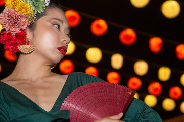 Beautiful Asian woman dressed as a gypsy at the Seville Fair with a background of lanterns at night - obrazy, fototapety, plakaty