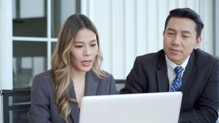 Obraz premium Asian businessman and businesswoman talking together in an office