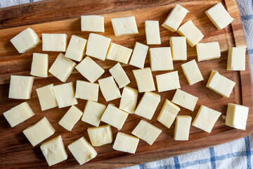 Paneer or Indian cottage cheese cut into cubes on a wooden chopping board. Top view.
