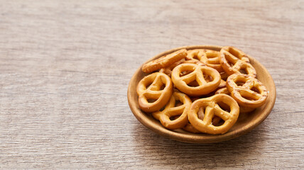 mini salted pretzel in a wooden plate on wood table background.                                           