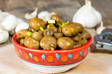 Vegan glazed button mushrooms with vegan butter, garlic in soy sauce. Fungi food. Fresh vegetarian snack or dinner. Champignon fungus. In oriental handmade Arabic bowl.