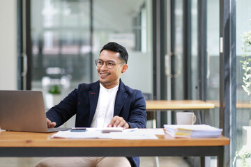 Fototapeta premium Successful and professional adult Asian businessman or male boss in formal suit working at his office desk.