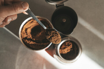 Metal coffee maker for brewing espresso on the stove. Teaspoon with ground coffee beans
