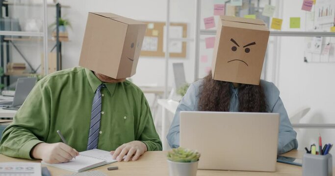 Office workers with paper bag heads showing emoji working at project at desks using laptops and taking notes. Emotions and workplace concept.