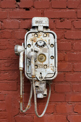 Old vintage telephone on a street brick wall. Steampunk technology, design, retro style concept.