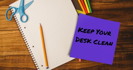 Composite of keep your desk clean on sticky note with pencil, scissors and notebook on table