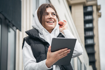 Fototapeta premium Business young woman with a tablet on the background of the building.