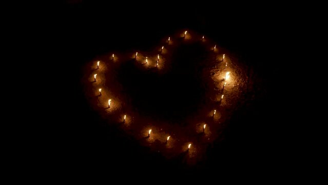 Burning torches in shape of heart glowing in darkness, aerial view.