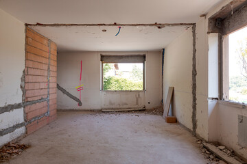 Large bright room with windows of an ancient villa undergoing renovation. The old walls have been...