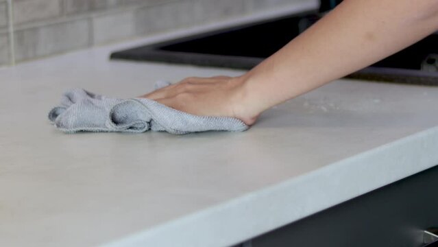 woman hand cleaning kitchen with gray microfiber cloth napkin and spray from bottle.black sink washstand basin in background.deep clean day tips dry wet wipe close up 4k real time video