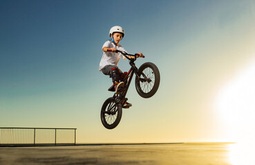 A teenager BMX Racing Rider performs tricks in a skate park on a pump track. - 533630974