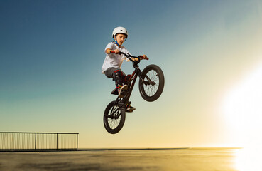 A teenager BMX Racing Rider performs tricks in a skate park on a pump track.