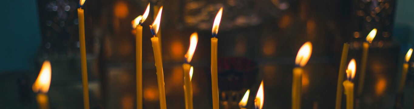 church candles close-up, against the background of a specially blurred religious cross