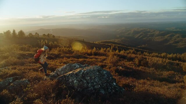 Woman hiker run into frame on top of mountain hill in beautiful cinematic sunset. Raise hands in excitement and success. Millennial outdoor lifestyle, freedom feeling in nature. Authentic happiness