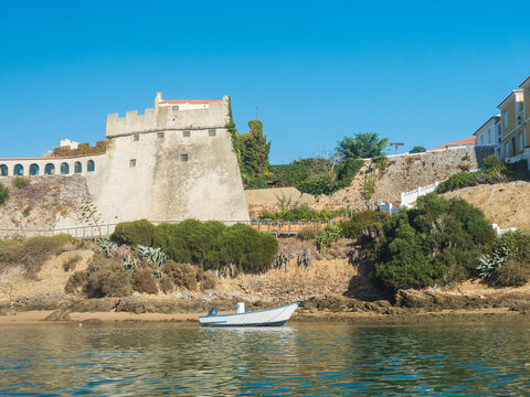 View of medieval fort Forte de Sao Clemente over the Mira river with small boat in sunny day with clear blue sky. Vila Nova de Milfontes, Portugal, Rota Vicentina coast