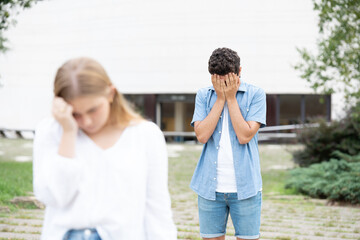 Standing teenager boy crying after breakup and sad girlfriend leaving him