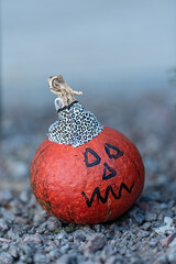 small orange pumpkin decorated for Halloween. a face was drawn and a cap was made