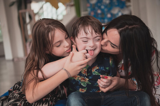 A girl and a woman hug a child with down syndrome in a modern preschool institution
