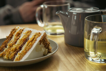 A piece of cake on a plate and a cup close-up on a table in a cafe.