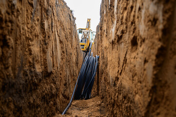 Installation of HDPE pipes in the trench. The process of laying of engineering systems water...