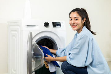 Happy beautiful housewife opening the front of the washing machine And is about to put the dirty laundry into the washing machine on weekends. Woman cleaning clothes.