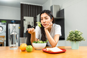 Unhappy female looking to organic greens vegetable salad in weight loss diet and wellness on table....