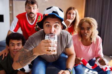 Obraz premium Football fans having fun drinking beer watching game on TV