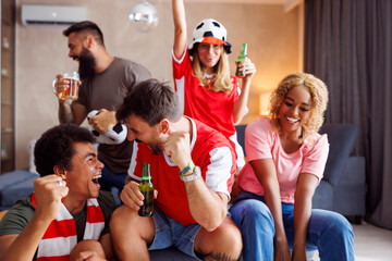 Group of friends cheering and celebrating while watching football on TV