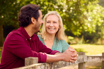 Mature Mother With Mixed Race Adult Son Leaning On Fence Walking In Countryside