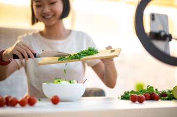 Smiling vlogger preparing a vegetable salad in her vlog