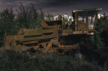Fototapeta na wymiar Abandoned combine harvester. Rusty spoiled combine harvester. Post-apocalyptic landscape.