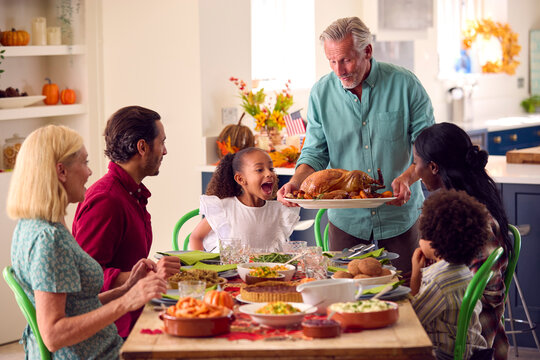 Grandfather Serving As Multi-Generation Family Celebrating Thanksgiving At Home Eating Meal Together