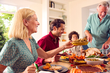 Grandfather Serving As Multi-Generation Family Celebrating Thanksgiving At Home Eating Meal Together