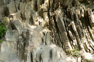 Fototapeta na wymiar Mountain landscape, beauty of wild nature, miracle created by nature. Photo of stone cliff with crevices and beautiful curves on sunny day. Tourism, hiking, uphill climb, summer trip.