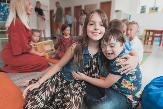 A girl and a boy with Down's syndrome in each other's arms spend time together in a preschool institution