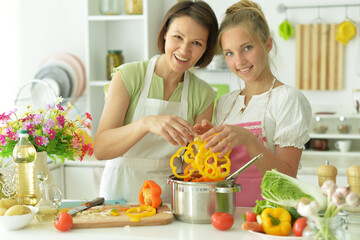 Beautiful girl with her mother preparing a salad in the kitchen