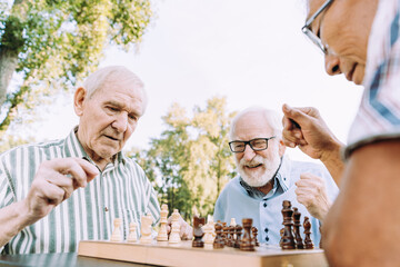 Group of senior friends playing chess at the park