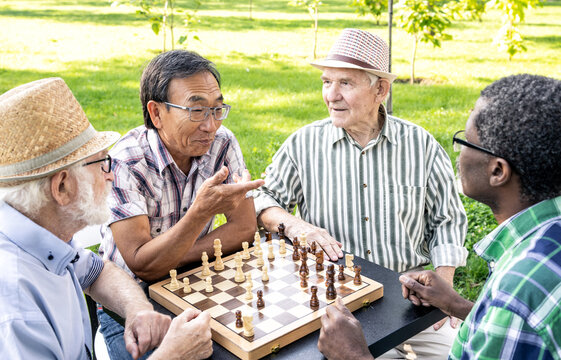 Group of senior friends playing chess at the park