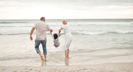 Family, children and beach with a girl and her grandparents by the sea or ocean in nature. Sand,...
