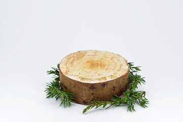 Wooden cut platform and juniper twigs on a white background. Empty natural exhibition podium for product presentation