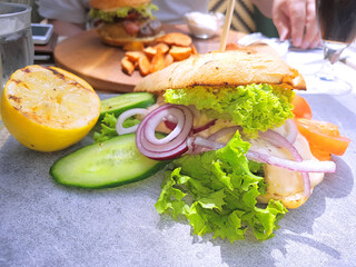Delicious sandwich with salad, cucumber, onions and lemon at a café