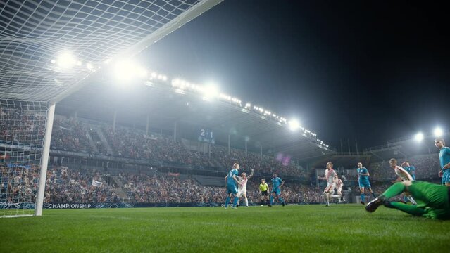 Football Championship: White Team Forward Hits the Ball and Scores Perfect Goal in Slow Motion. Goalkeeper Jumps and Fails to Catch, Protect Goals. Crowd of Fans Cheers. Playback in Cinematic Front